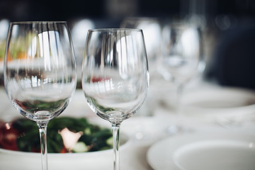 Close-up of empty wine glasses on wedding table in focus.