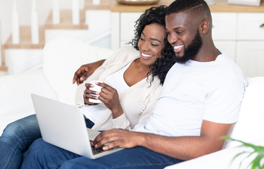 Fototapeta premium Happy African American man and woman enjoying movie on laptop