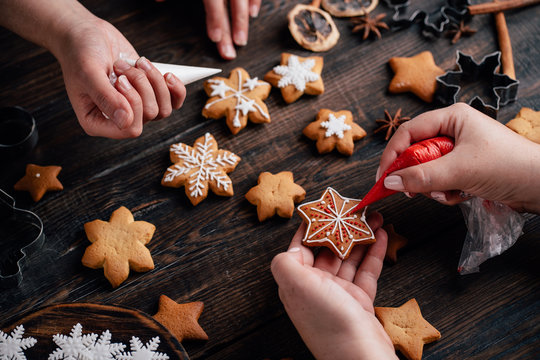 Christmas and New Year holidays, family weekend activities, celebration atmosphere. Friends decorating traditional gingerbread cookies - Powered by Adobe