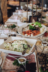 View over delicious dishes served on wedding table. Salads and appetizers, dishes and utensils.