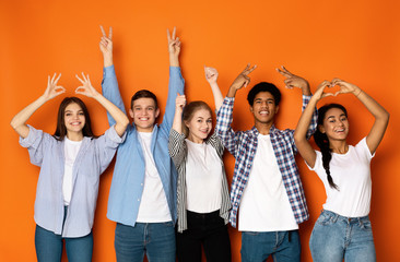 Young friends gesturing with hands over orange background