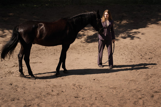 photo girl trainer in a suit interacts with her horse