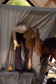 photo long-haired girl leaned near a horse gray background