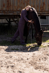 Pictures beautiful woman in a suit hugs her horse