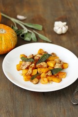 dish with pumpkin. fried chicken fillet and pumpkin cubes with sage (chips from sage). a dish on the table on a sunny day. autumn dish with pumpkin.