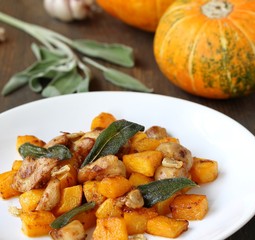 dish with pumpkin. fried chicken fillet and pumpkin cubes with sage (chips from sage). a dish on the table on a sunny day. autumn dish with pumpkin.