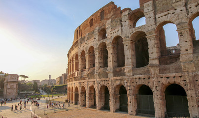Fototapeta premium FLAVIAN THEATRE, ROME, ITALY - 2018: Many people gather at the Colosseum entrance at sundown.