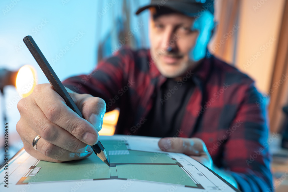 Poster work on a construction project. the man makes notes in the construction plan. hand with a pencil clo
