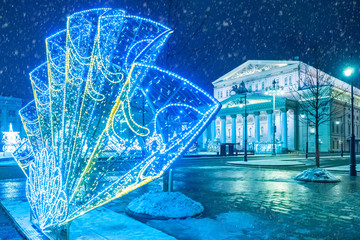 Moscow in New year. Christmas in Russia. Bolshoi theatre on a festive evening. Snow falls on Theatre square. The square is decorated with sculptures of garlands. Fan of garlands on the Theater square.