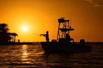 Man silhouette fishing on a boat