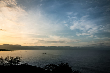 Sunrise over Lake Tanganyika with silhouettes of several traditional fishing boats. Tanzanian mountains in the background