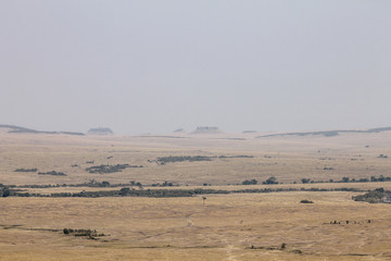 Fototapeta na wymiar View over the Mara River marking the Border Between the Maasai Mara in Kenya and the Serengeti in Tanzania. Ancient Volcanoes in the Background on the Horizon