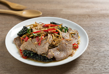 close up of stir fried sizzle pork in a ceramic dish on wooden table. asian homemade style food concept.