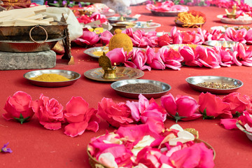 Indian wedding ceremony, decorations for traditional ethnic rituals for marriage, fire burning, flowers and statuettes of the deity on red carpet