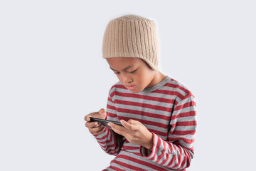 Little asian boy in wool hat using smart phone on white background