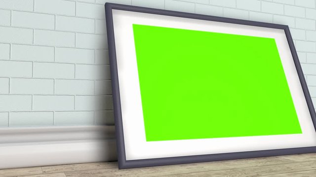 A picture or photo frame with a green screen on the background of a brick wall of an office or room.
