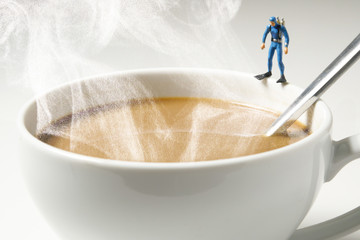 scuba diver miniature man standing on white coffee cup