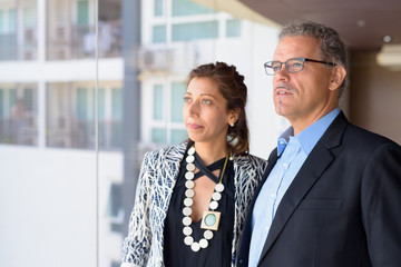 Hispanic business couple together looking out the window of office building