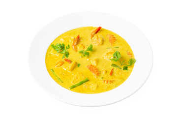 Closeup plate of thai yellow curry soup with coconut milk, shrimps, pineapple, carrot and green beans isolated at white background.