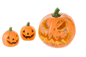 Two orange ceramic pumpkins with eyes nose and mouth and a large pumpkin with eyes and mouth, isolated on a white background.