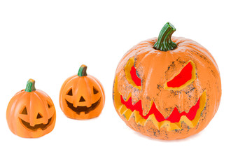 Two orange ceramic pumpkins with eyes nose and mouth and a large pumpkin with eyes and mouth with red light, isolated on a white background.