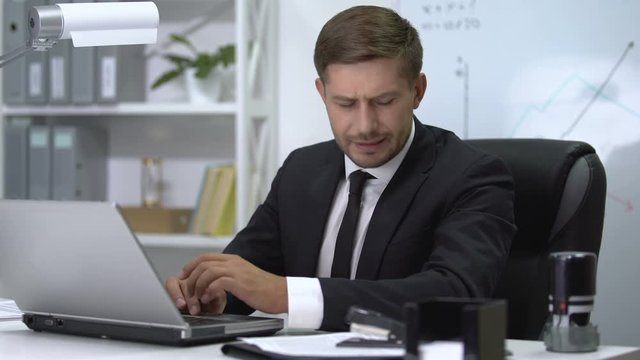 Young businessman suffering shoulder pain during typing on laptop, sprain result