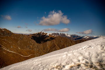 Above the snow line at the top pf Roys Peak with views of the Southern Alps Wanaka