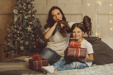 Family celebrates Christmas. Cozy christmas morning. Mum and daughter give each other Christmas presents. Gift boxes. Merry Christmas and happy holidays. Tenderness, care and mutual understanding