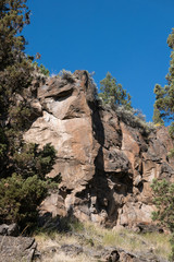 Rocky cliffs, trees and clear blue sky, vertical