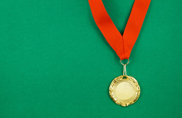 Gold medal with red ribbon on green background