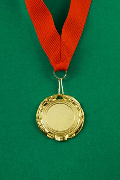 Gold medal with red ribbon on green background