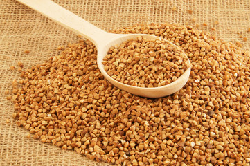 Buckwheat with wooden spoon on rustic burlap sack background