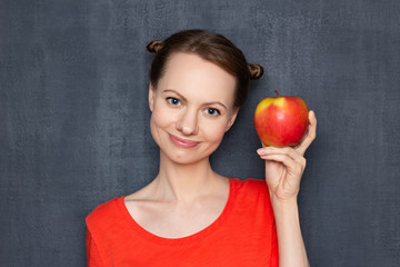 Portrait of happy young woman holding ripe yellow-red apple