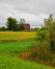 View of an old red barn in a farm field during the Autumn season