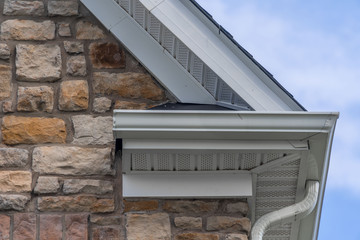 Gable with colored stone siding, white frame gutter guard system, fascia, drip edge, soffit, on a...