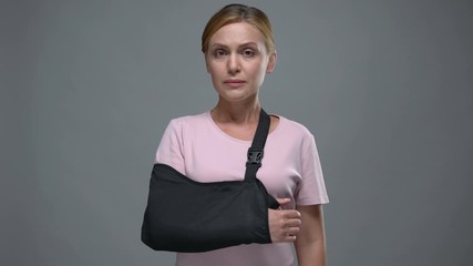 Upset woman with arm sling looking into camera, fracture or sprain, trauma