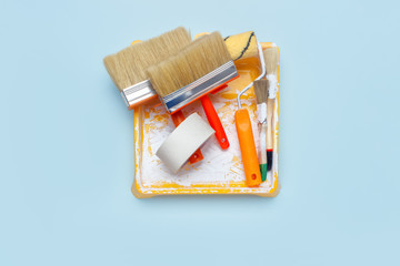 Set of tools for painting: paint brushes, masking tape, paint roller on  light blue background....