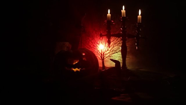 Horror concept. Scary Halloween pumpkin with carved eyes and a smile with burning candles and an ax on a dark toned background. Empty space. Selective focus