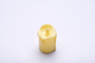 White candle on white background isolated. Small candle with light yellow spots on light background. Christmas decor
