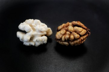 Young peeled and old walnut on a black plate