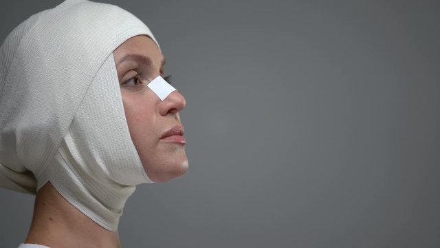 Woman in headwrap standing on grey background, skull injury, accident result