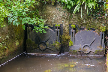 A pair of metal sluice gates in a river in Cornwall