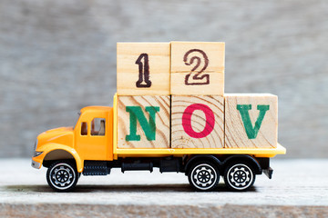 Truck hold letter block in word 12nov on wood background (Concept for date 12 month November)