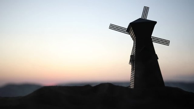 Windmill silhouette standing on hill against the sunset sky. Selective focus