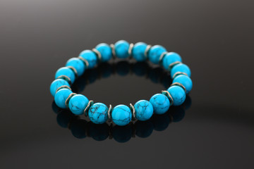 Bracelet of bijouterie jewelry made of turquoise and gold on a gray black background