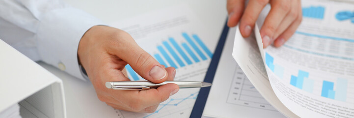 Male hands hold documents with financial statistics at office workspace closeup. White collar check money papers stock exchange market internal Revenue Service inspector earning list concept