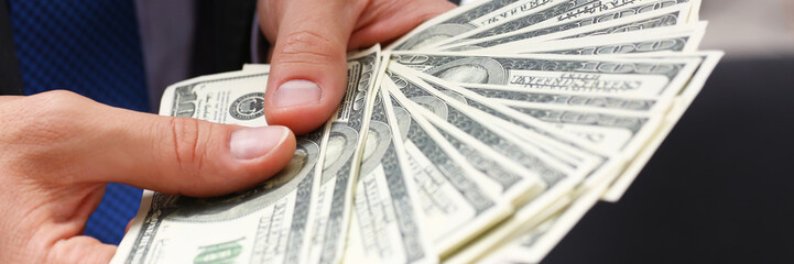 Man in suit and tie hold in arm pack of hundred dollar bills closeup. Stock market exchange earn...