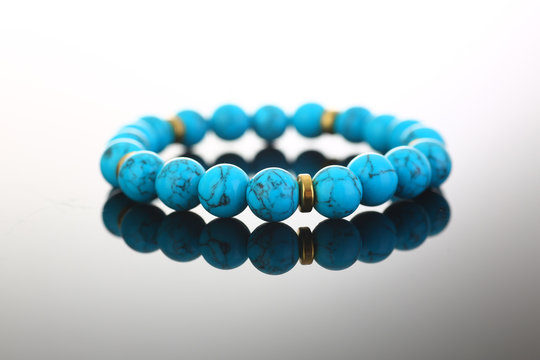 Bracelet of bijouterie jewelry made of turquoise and gold on a gray black background