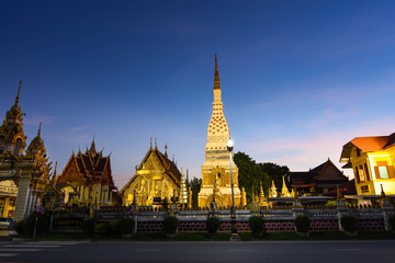 Naklejka premium The golden pointed pagoda and the light at dusk. Buddhist tourist spots in Isan, Thailand, Southeast Asia
