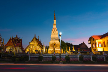Fototapeta premium The golden pointed pagoda and the light at dusk. Buddhist tourist spots in Isan, Thailand, Southeast Asia